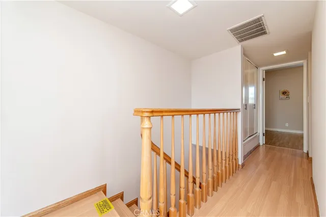 a view of a hallway with wooden floor and a bathroom