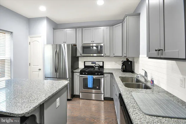 a kitchen with granite countertop a sink and stainless steel appliances