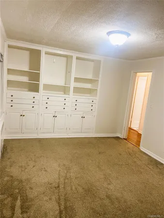 an empty room with cabinet and windows