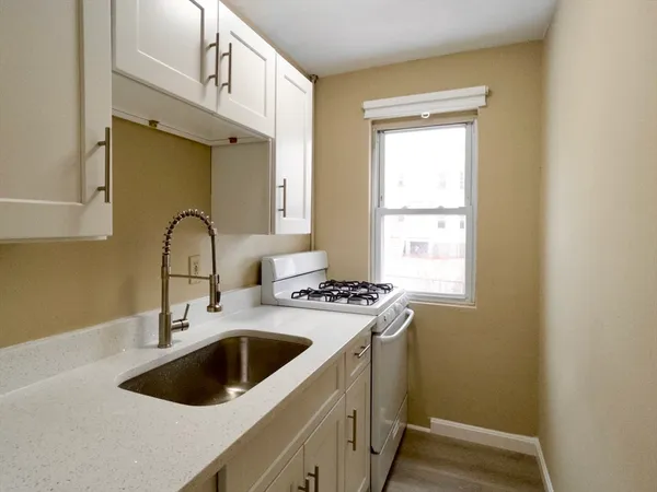 a kitchen with a sink a stove a window and cabinets