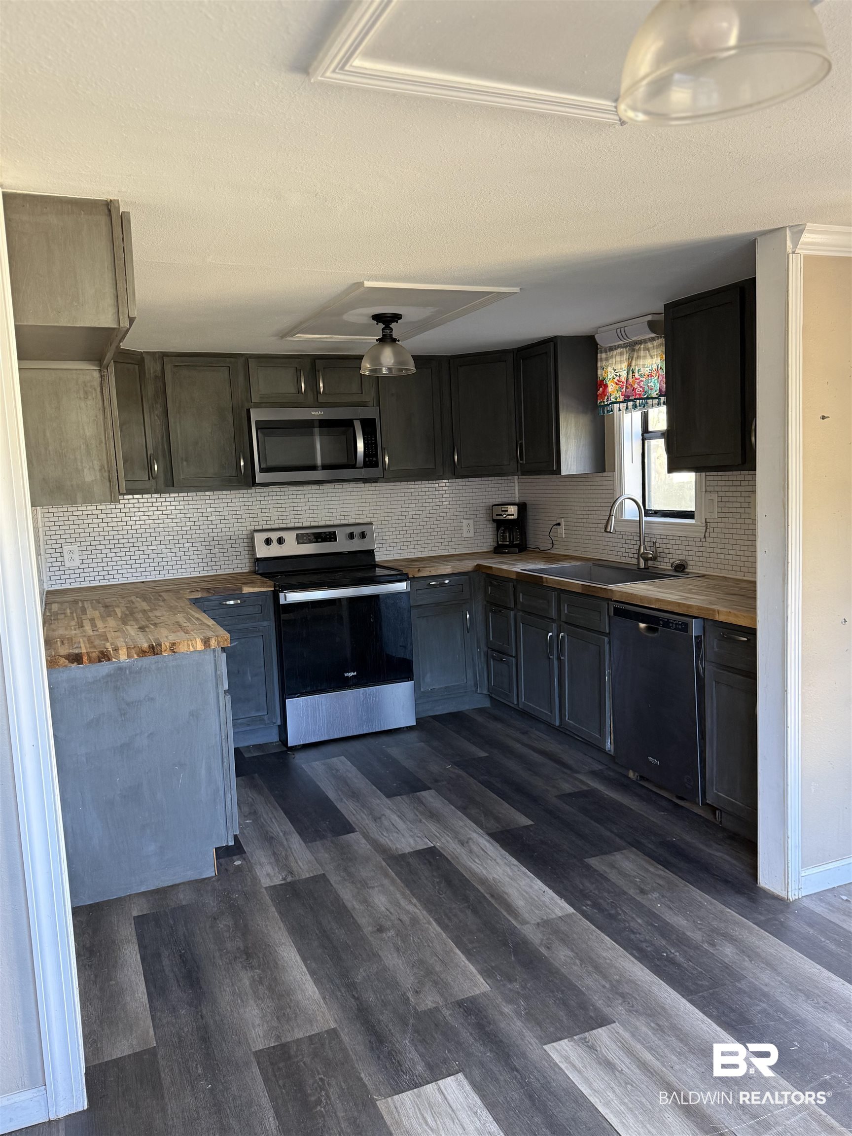 6745 Carol Plantation Road Theodore, AL 36582 - Photo 3 of 13 Kitchen with butcher block counters, appliances with stainless steel finishes, dark wood-style flooring, decorative backsplash, and a textured ceiling