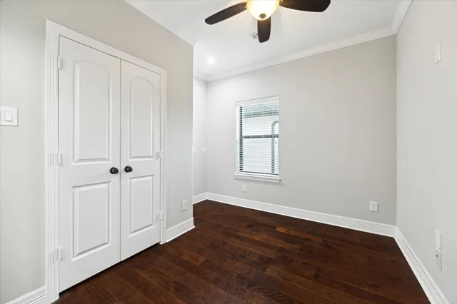 an empty room with wooden floor chandelier fan and windows