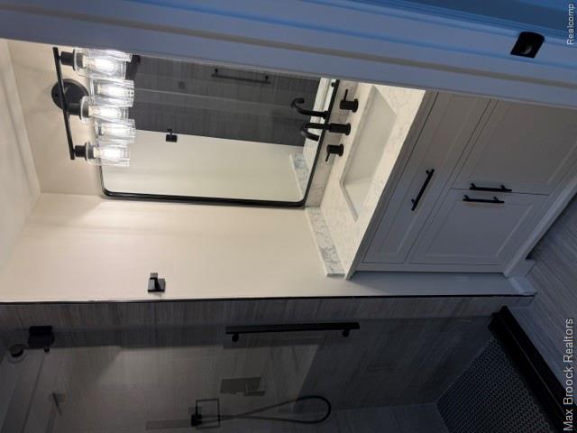 650 Deerfield Court Rochester, MI 48309 - Photo 17 of 28 Modern primary bathroom featuring a floating vanity with white quartz countertop, matte black hardware and faucet, and a four-light vanity fixture