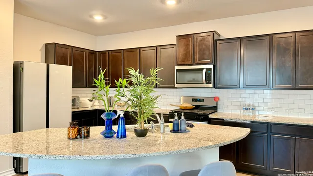 a kitchen with stainless steel appliances granite countertop a refrigerator a sink a stove a microwave a counter top and cabinets