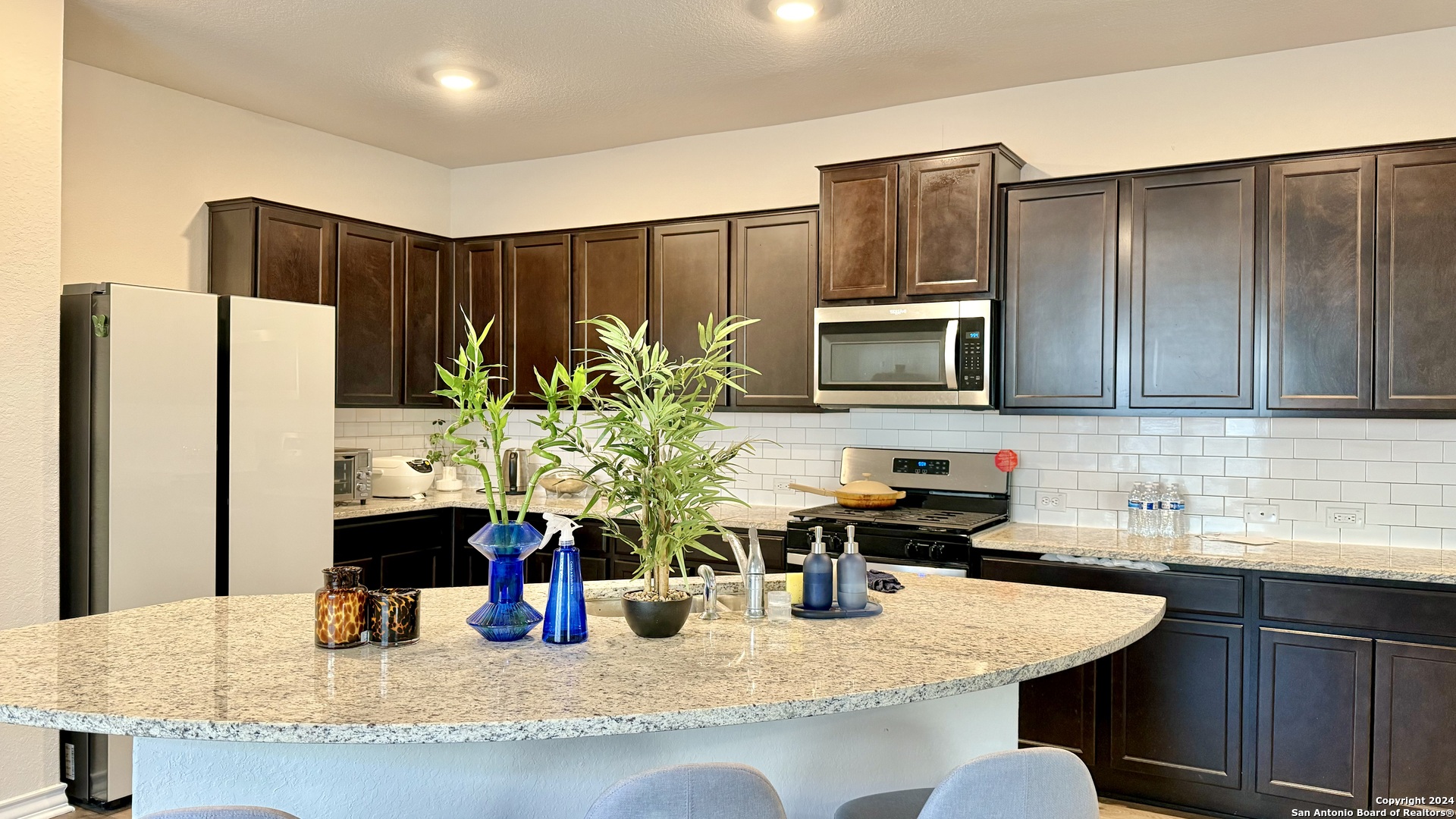 13535 Boothe Grove San Antonio, TX 78254 - Photo 4 of 7 a kitchen with stainless steel appliances granite countertop a refrigerator a sink a stove a microwave a counter top and cabinets