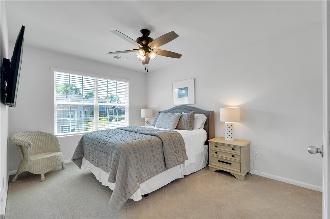453 Bee Cv Way Pendleton, SC 29670 - Photo 19 of 25 A well-appointed guest bedroom featuring a large window, plush carpet, and a ceiling fan for ultimate comfort.
