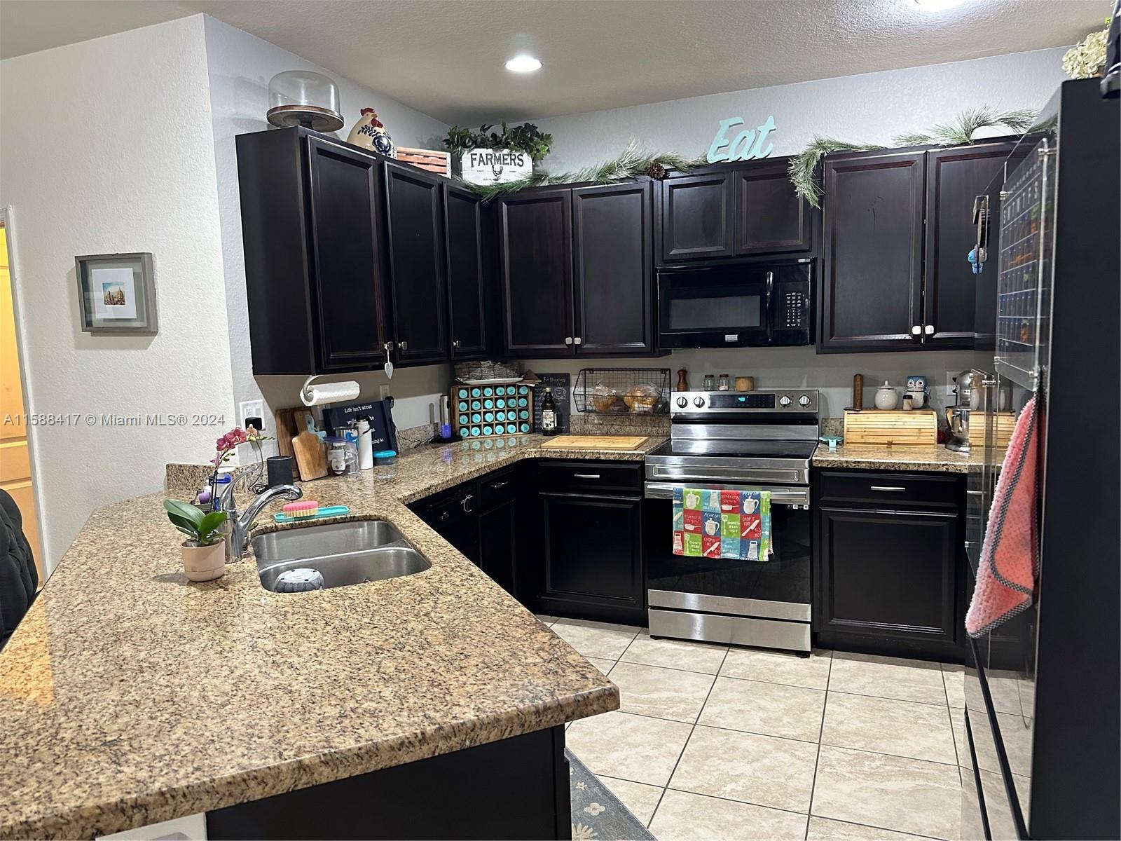 11606 Southwest 245 Terrace Homestead, FL 33032 - Photo 11 of 27 a kitchen with kitchen island granite countertop a sink counter top space appliances and cabinets