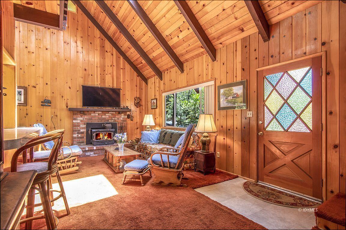 25075 Wood Road Idyllwild, CA 92549 - Photo 8 of 21 a living room with furniture a rug floor to ceiling windows and a flat screen tv