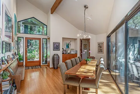 a dining room with furniture large windows wooden floor and a chandelier