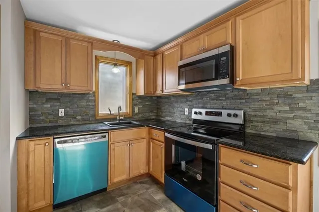 a kitchen with granite countertop a stove top oven microwave and cabinets