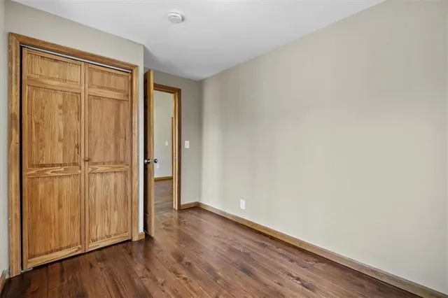 an empty room with wooden floor and closet area