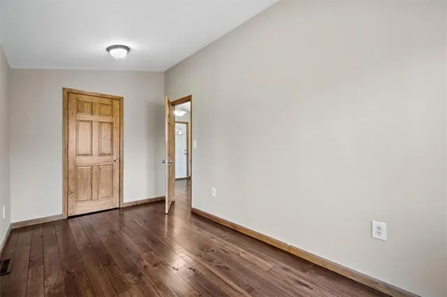a view of an empty room with wooden floor and closet