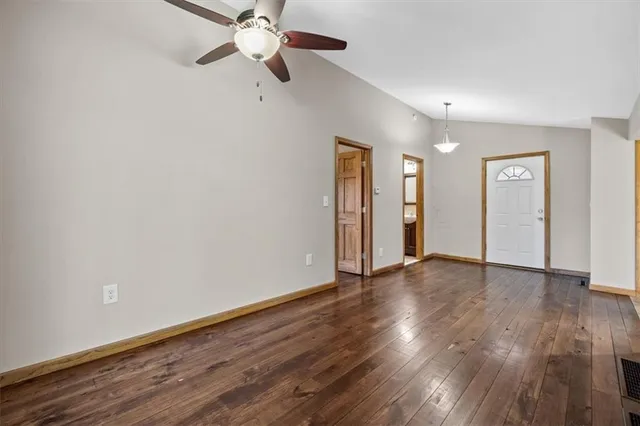 a view of an empty room with wooden floor and a ceiling fan