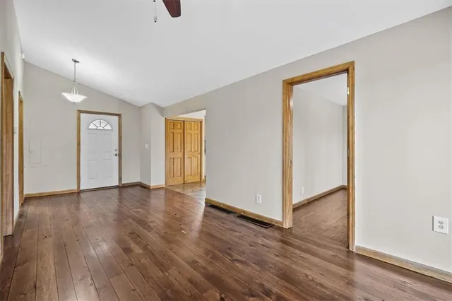 a view of an empty room with wooden floor and a window