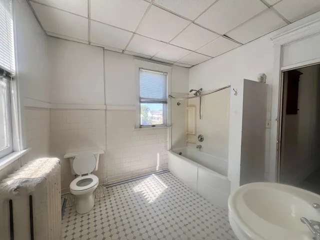 a bathroom with a granite countertop bathtub shower sink and toilet