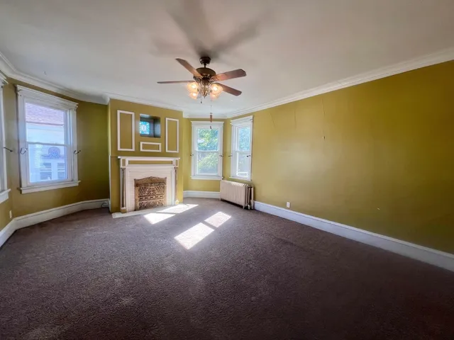 a view of empty room with fireplace and fan