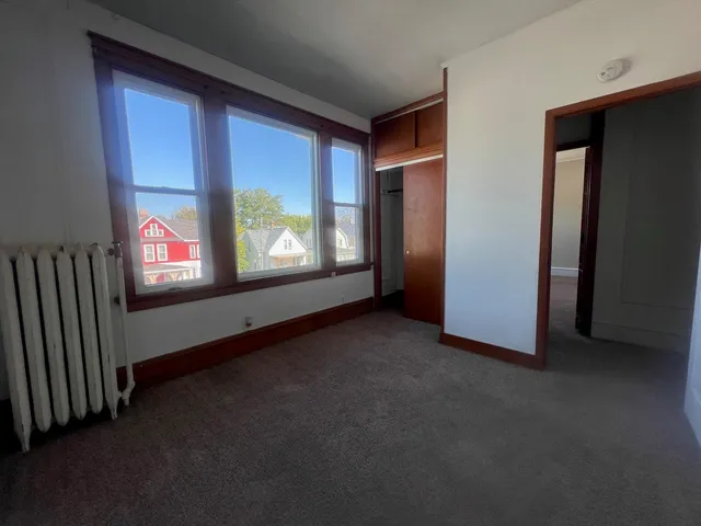 a view of an empty room with windows and a fireplace