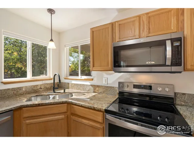 a kitchen with granite countertop a sink a stove microwave and cabinets