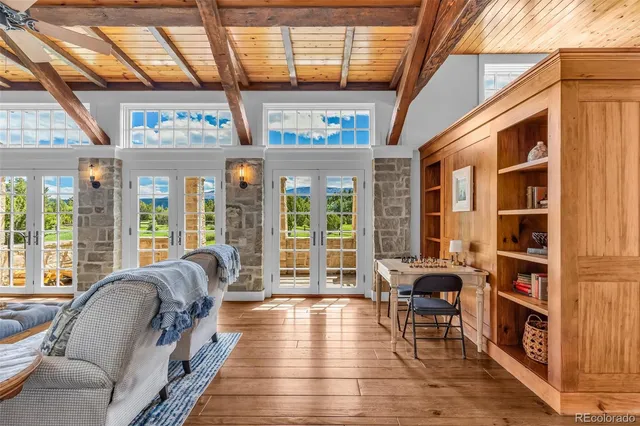 a living room with furniture floor to ceiling window and wooden floor