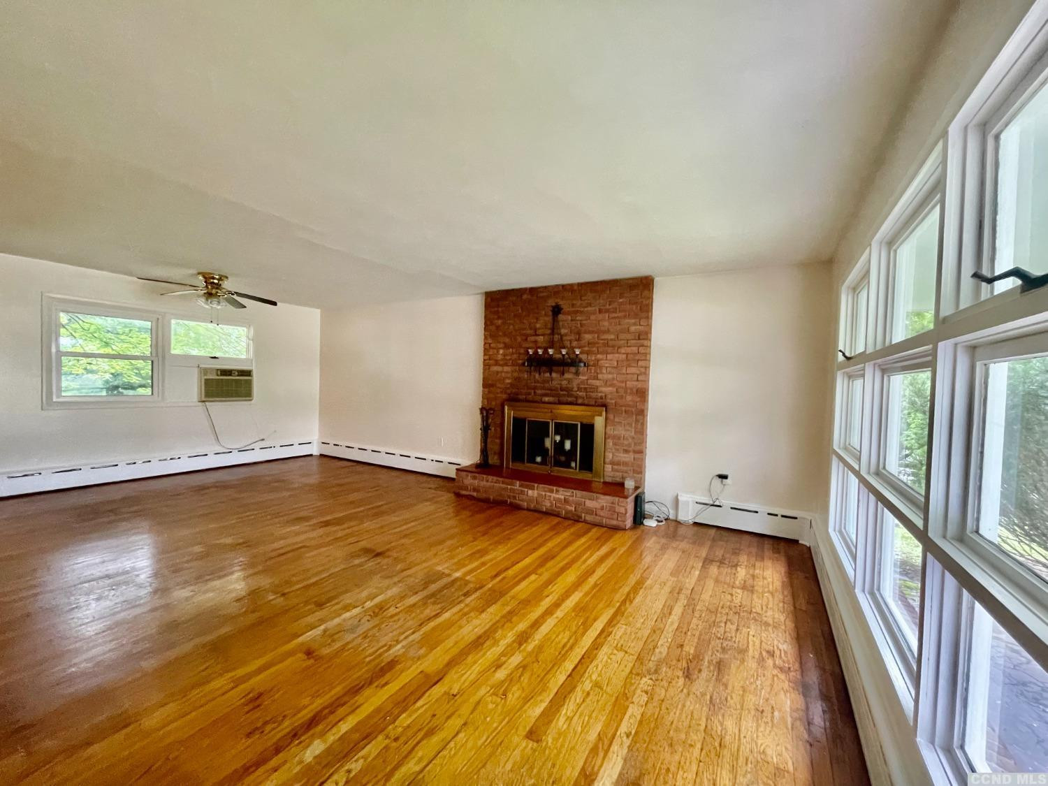 14 Cairo Junction Road Catskill, NY 12451 - Photo 3 of 25 an empty room with wooden floor fireplace and windows