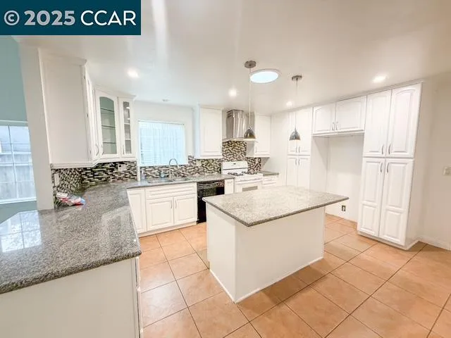 a kitchen with kitchen island granite countertop a sink and white cabinets