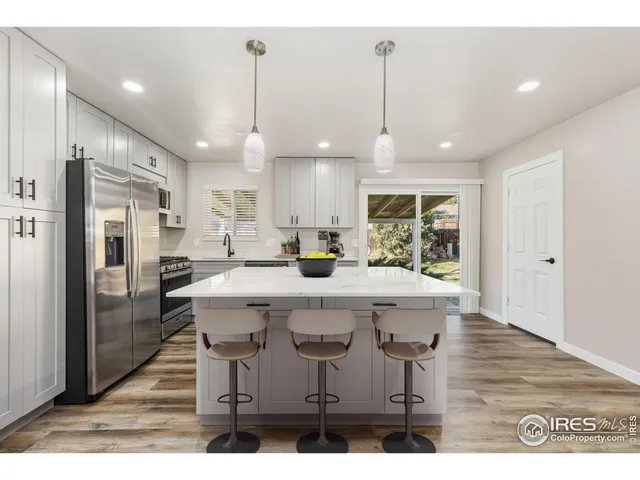 a kitchen with stainless steel appliances a dining table chairs refrigerator and sink