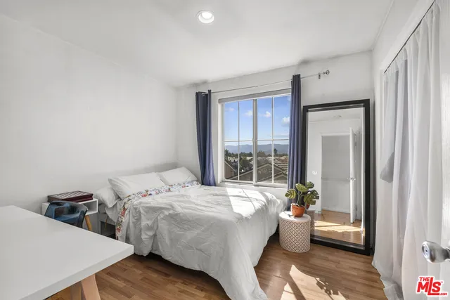 a room with a bed and large window with kitchen view