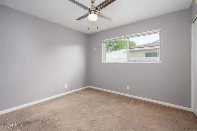 an empty room with windows and fan