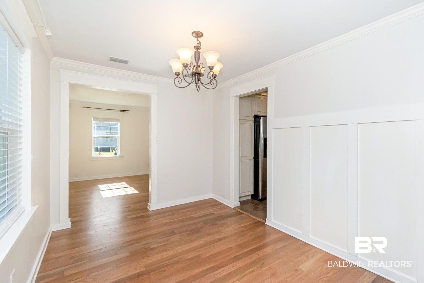 10 South Hathaway Road Mobile, AL 36608 - Photo 16 of 46 Unfurnished dining area featuring a chandelier, light wood-type flooring, crown molding, and a decorative wall