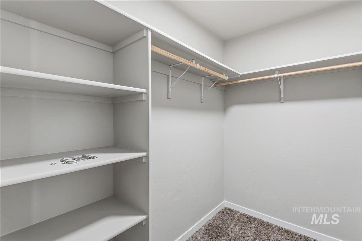 3091 S Green Boise, ID 83709 - Photo 21 of 27 Walk-in closet featuring built-in shelving, two levels of hanging rods, and neutral-toned carpeting