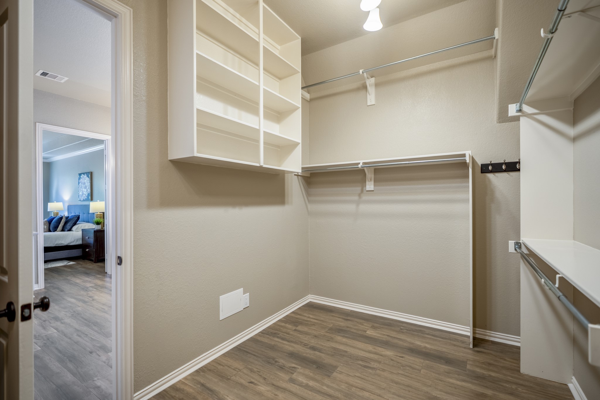 2407 Hendricks Lakes Drive Spring, TX 77388 - Photo 21 of 50 Another view of the primary walk-in closet shows the storage continuing with built-in shelving, hanging space, and wide-plank wood-look tile carried through from the suite. The doorway on the left leads back toward the remodeled primary bath, keeping the closet connected to the bath and bedroom for a smooth, private flow within the primary retreat.
