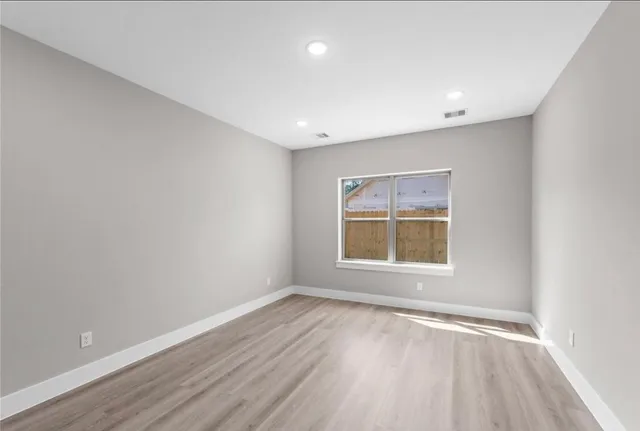 an empty room with a window and wooden floor