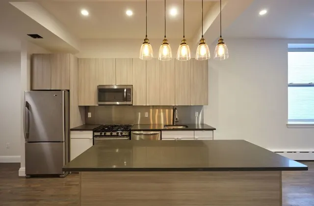 a kitchen with kitchen island a counter top space cabinets and stainless steel appliances