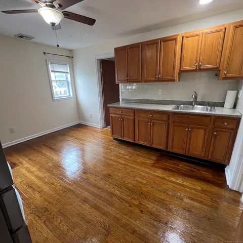a kitchen with stainless steel appliances granite countertop a sink a stove cabinets and wooden floor