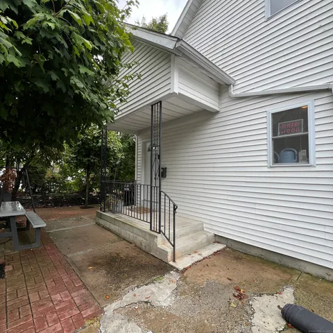 a view of a white house with a small yard and a large tree