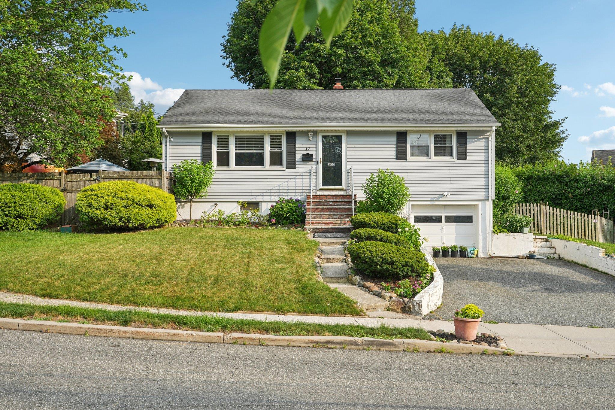 View of front of house with a garage, asphalt driveway, and roof with shingles