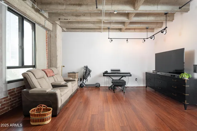 a bedroom with a bed a desk and chair with wooden floor