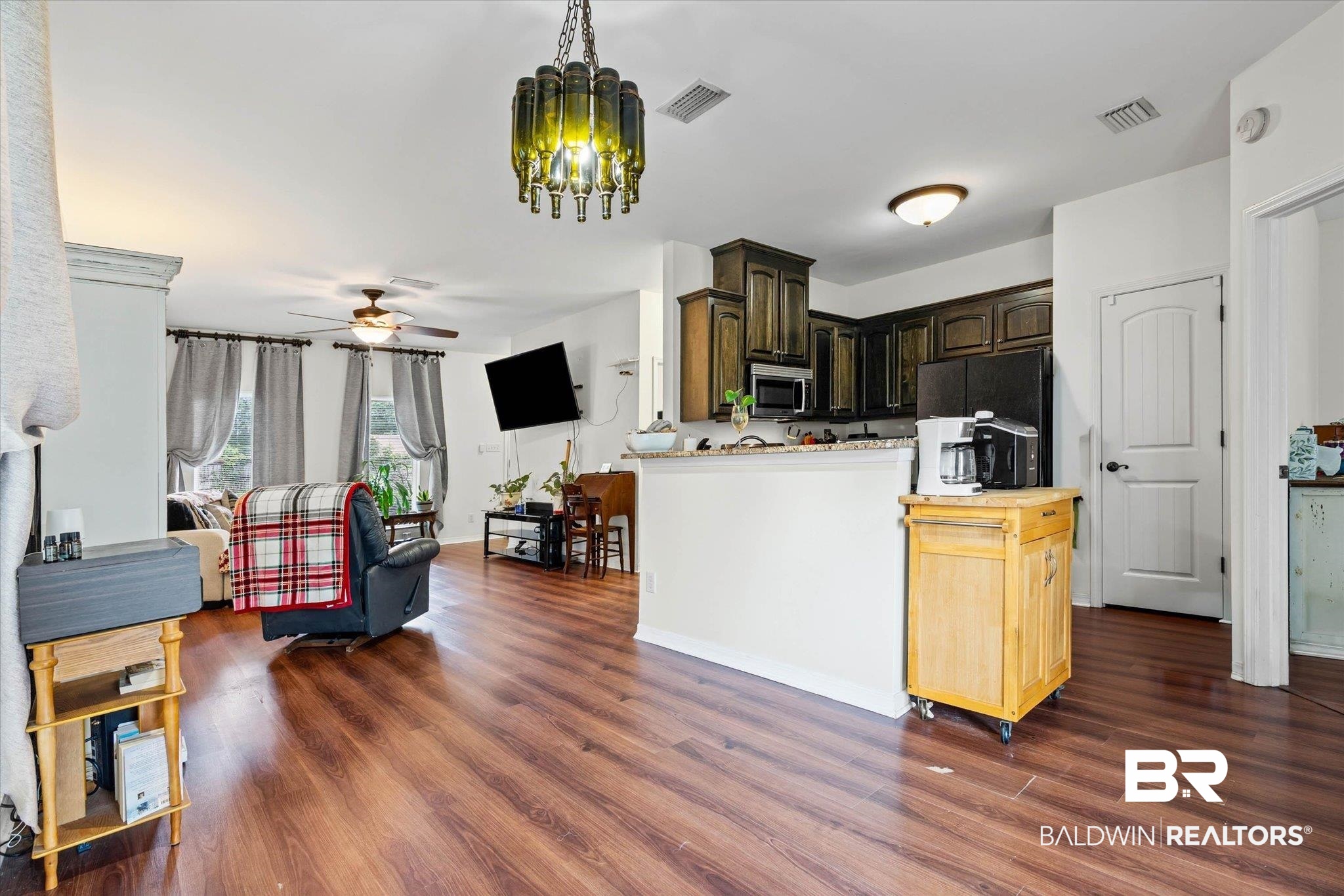 800 Galoway Avenue Mobile, AL 36609 - Photo 9 of 22 Open-concept living space featuring wood-finish flooring, a kitchen with dark cabinetry, and a central island with a light-toned countertop