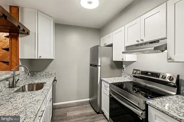 a kitchen with stainless steel appliances granite countertop a stove a refrigerator and a sink