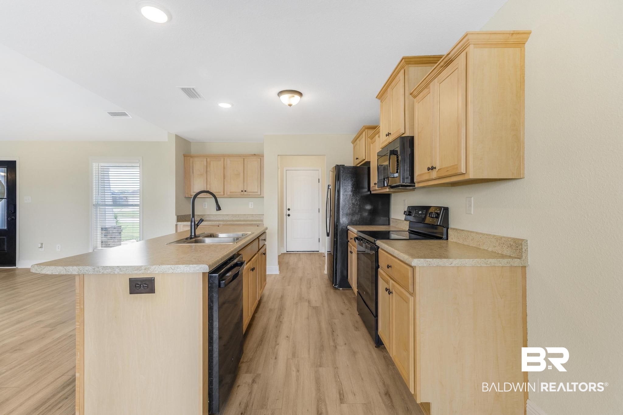 21580 Talbot Lane Robertsdale, AL 36567 - Photo 12 of 25 Kitchen with light brown cabinetry, black appliances, a center island with sink, light wood-style flooring, and light countertops