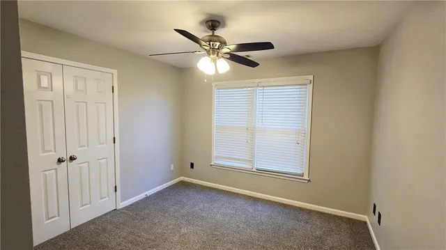 an empty room with a window and a ceiling fan