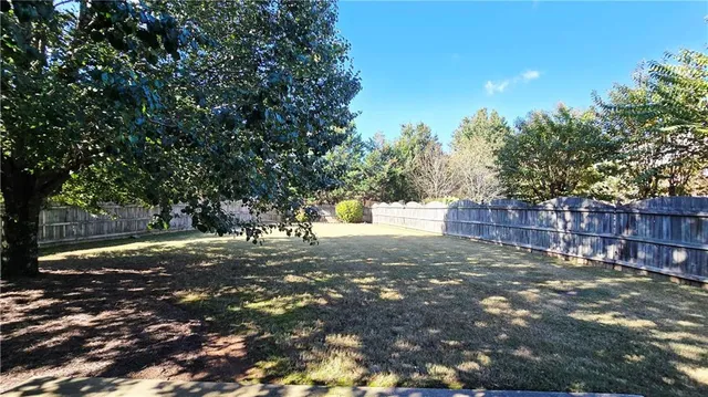 a view of a yard with large trees and wooden fence