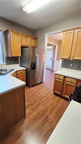 a kitchen with stainless steel appliances a refrigerator a sink a stove and wooden floor