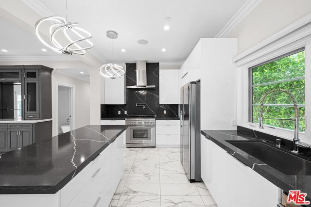 a large kitchen with stainless steel appliances granite countertop a lot of counter space and a large window