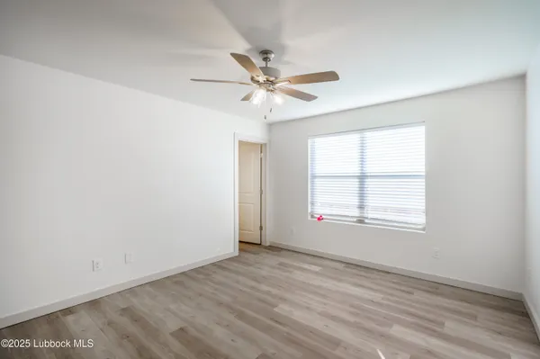 an empty room with a window and a ceiling fan