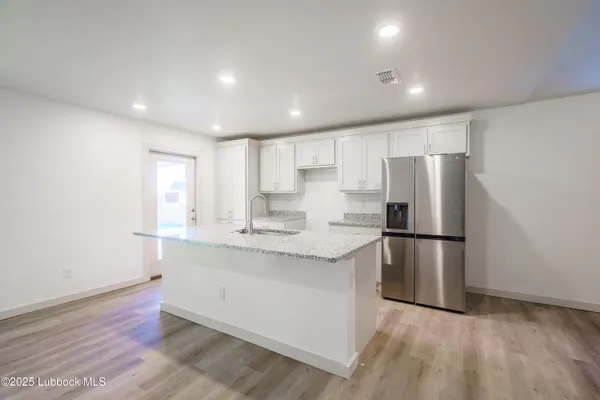 a kitchen with kitchen island a refrigerator sink and cabinets