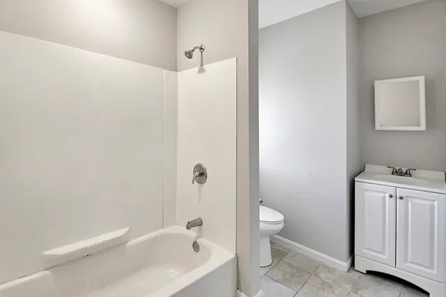 a bathroom with a granite countertop sink a toilet and shower