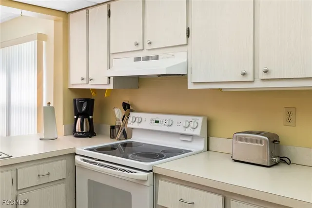 a kitchen with white cabinets and sink