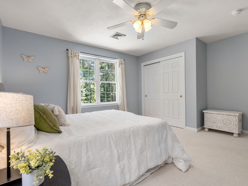 13 Breakneck Hill Road, Unit 1 Hopkinton, MA 01748 - Photo 30 of 37 a bedroom with a bed and a chandelier