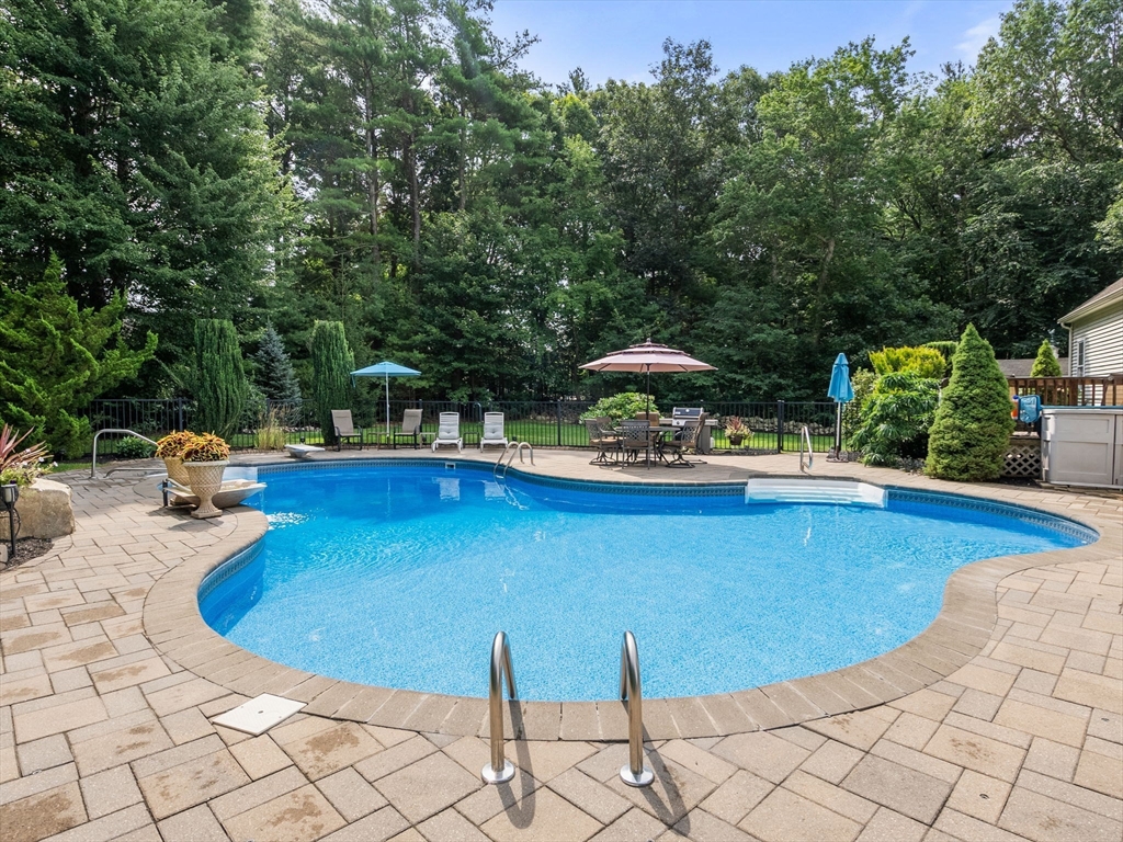 13 Breakneck Hill Road, Unit 1 Hopkinton, MA 01748 - Photo 6 of 37 a view of a swimming pool with lawn chairs under an umbrella